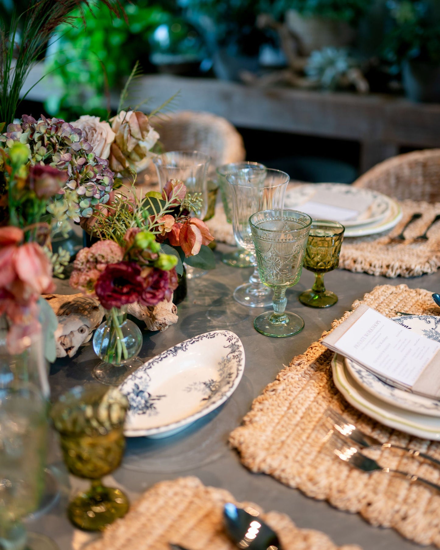 Elegant table setting with floral arrangements, glassware, and cutlery in a rustic indoor setting.